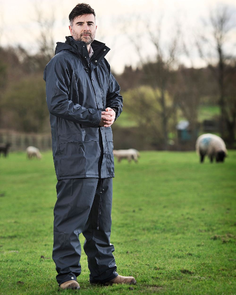 Navy coloured Fort Fortex Flex Waterproof Trousers on green blurry background