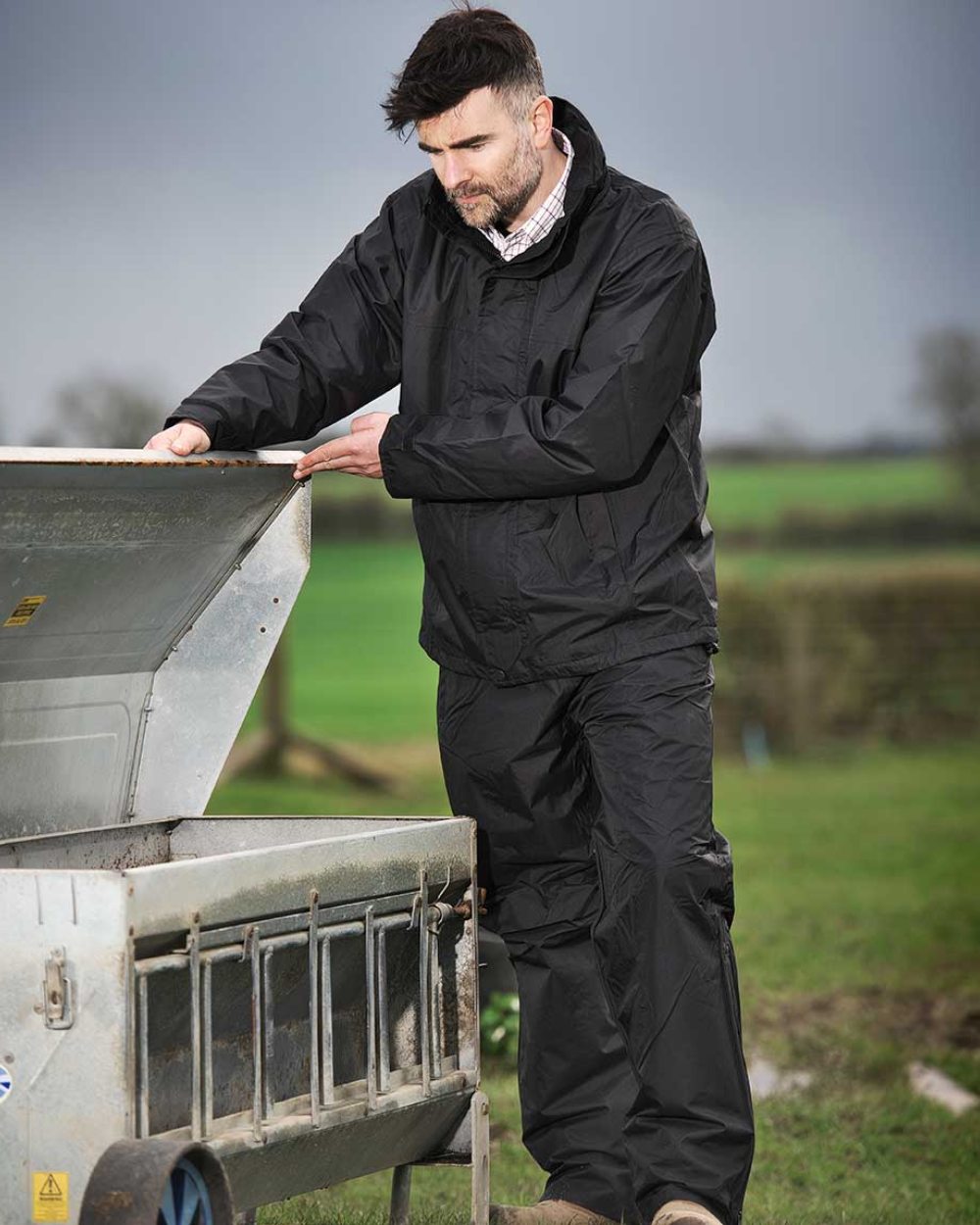 Black coloured Fort Rutland Waterproof Over Trousers on farm background