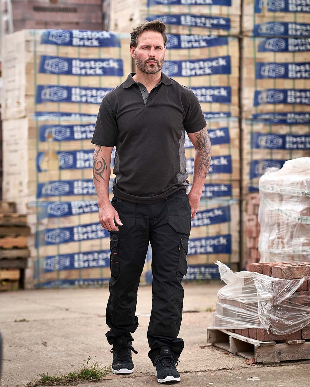 Black Coloured TuffStuff Elite Work Trousers On A Warehouse Background