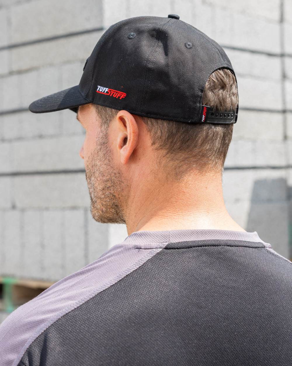 Black coloured TuffStuff Baseball Cap on construction background