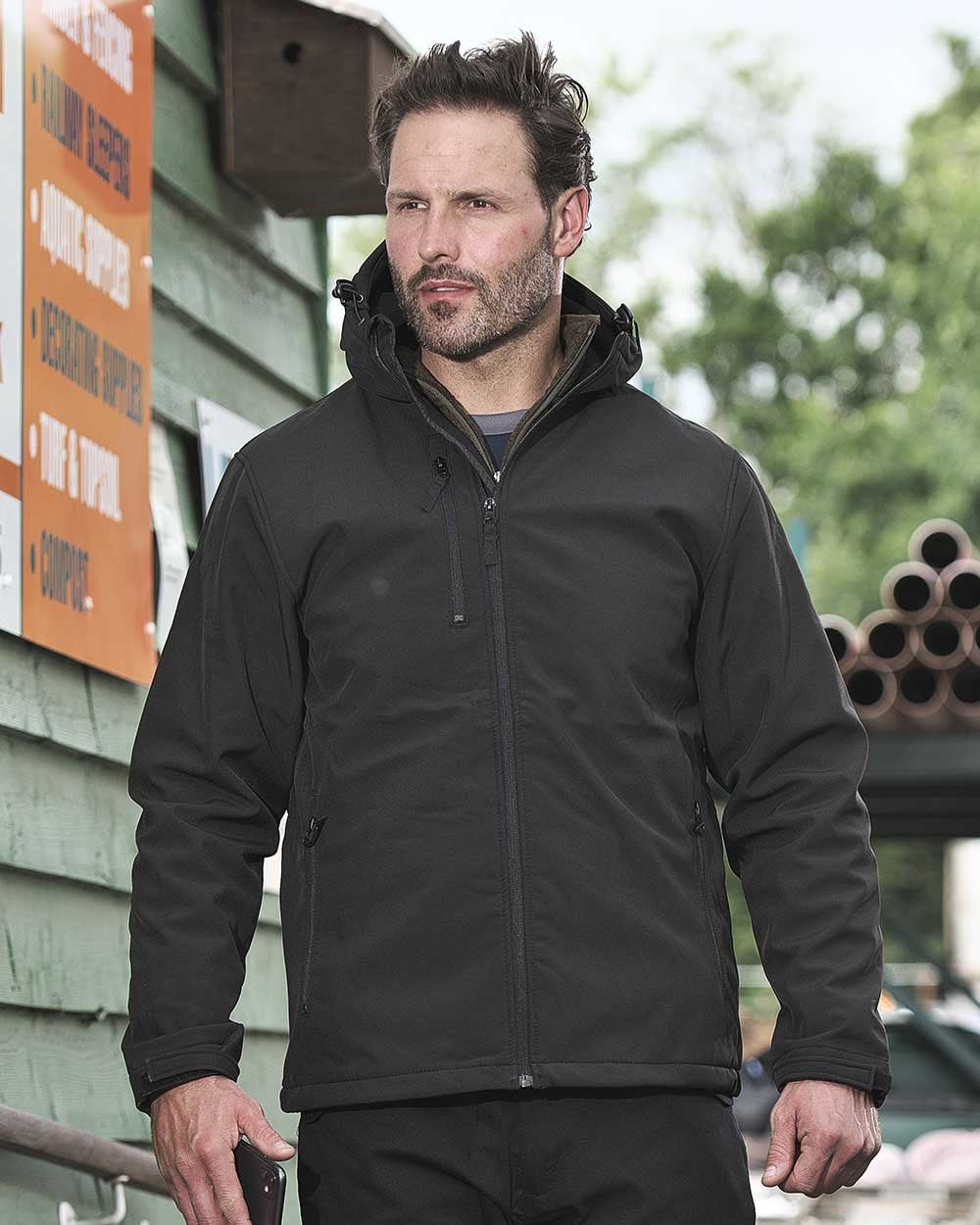 Black Coloured Fort Holkham Hooded Softshell Jacket On A Warehouse Background