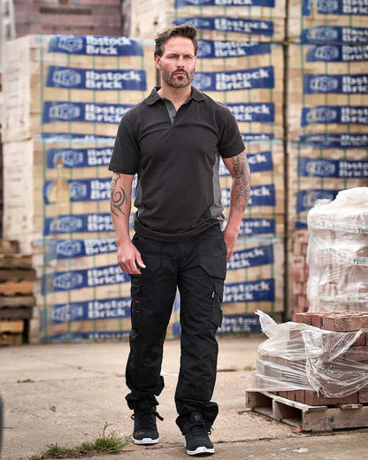 Black Coloured TuffStuff Elite Work Trousers On A Warehouse Background 
