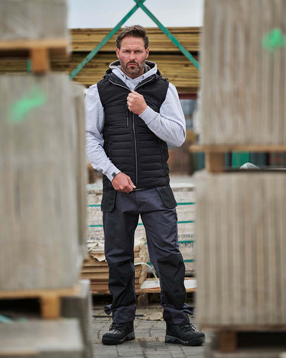 Grey Coloured TuffStuff Excel Work Trousers On A Warehouse Background 