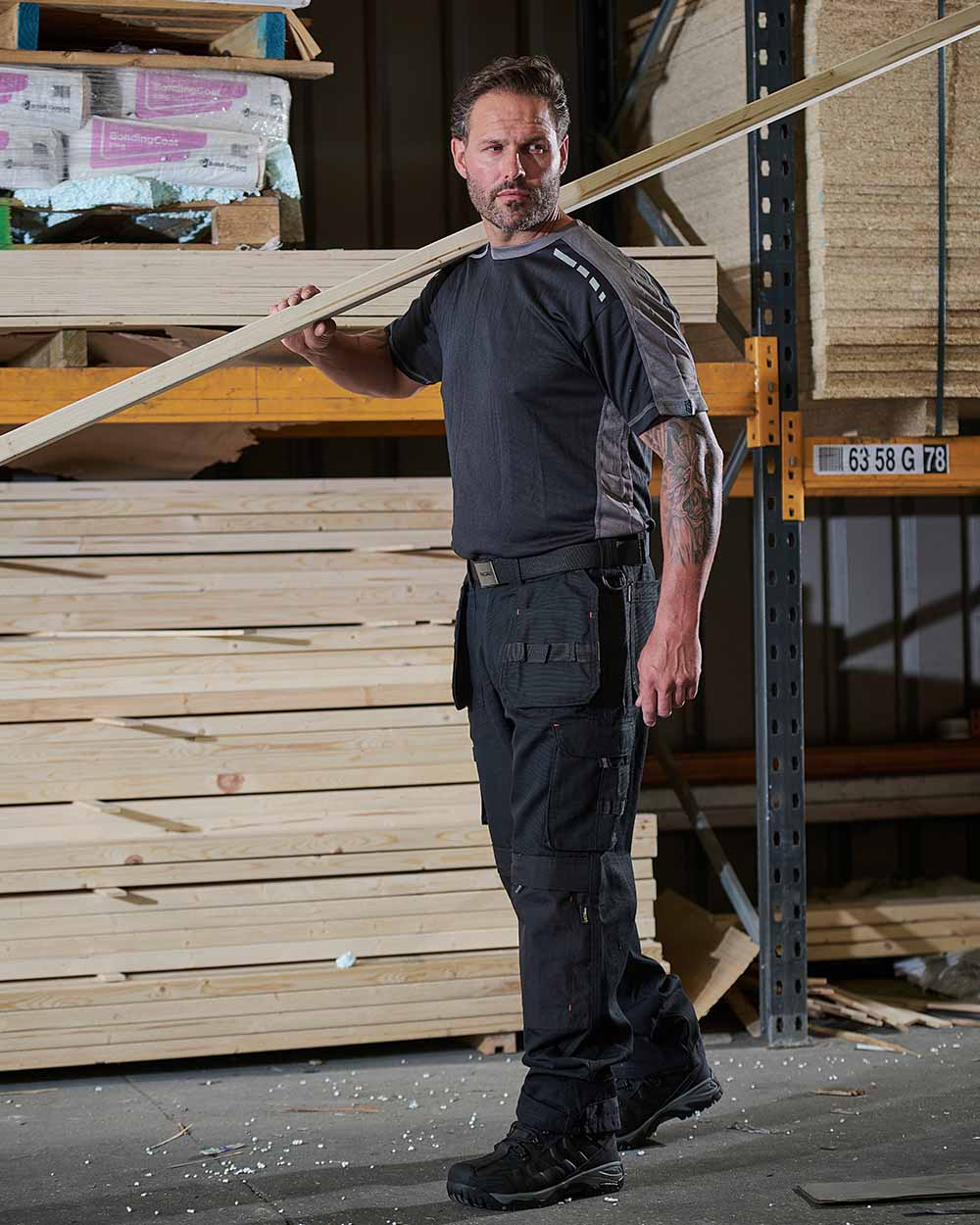 Black Coloured TuffStuff Extreme Work Trousers On A Warehouse Background 