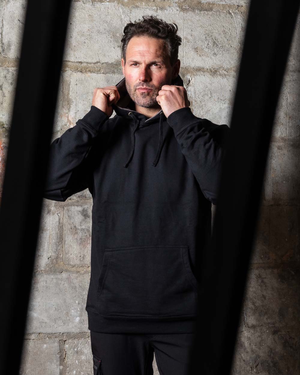 Black Coloured TuffStuff Hendon Hoodie On A Warehouse Background 