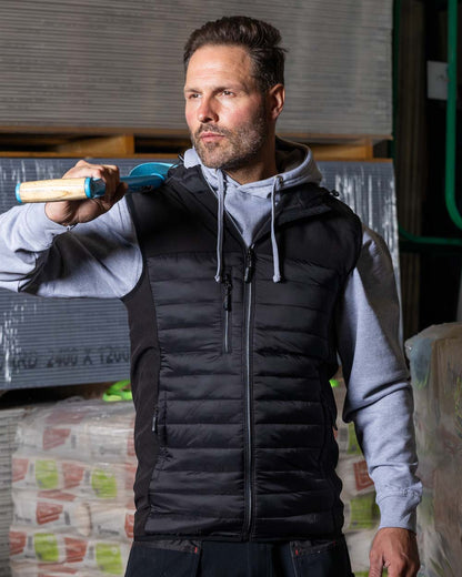 Black Coloured TuffStuff Howden Hooded Bodywarmer On A Warehouse Background