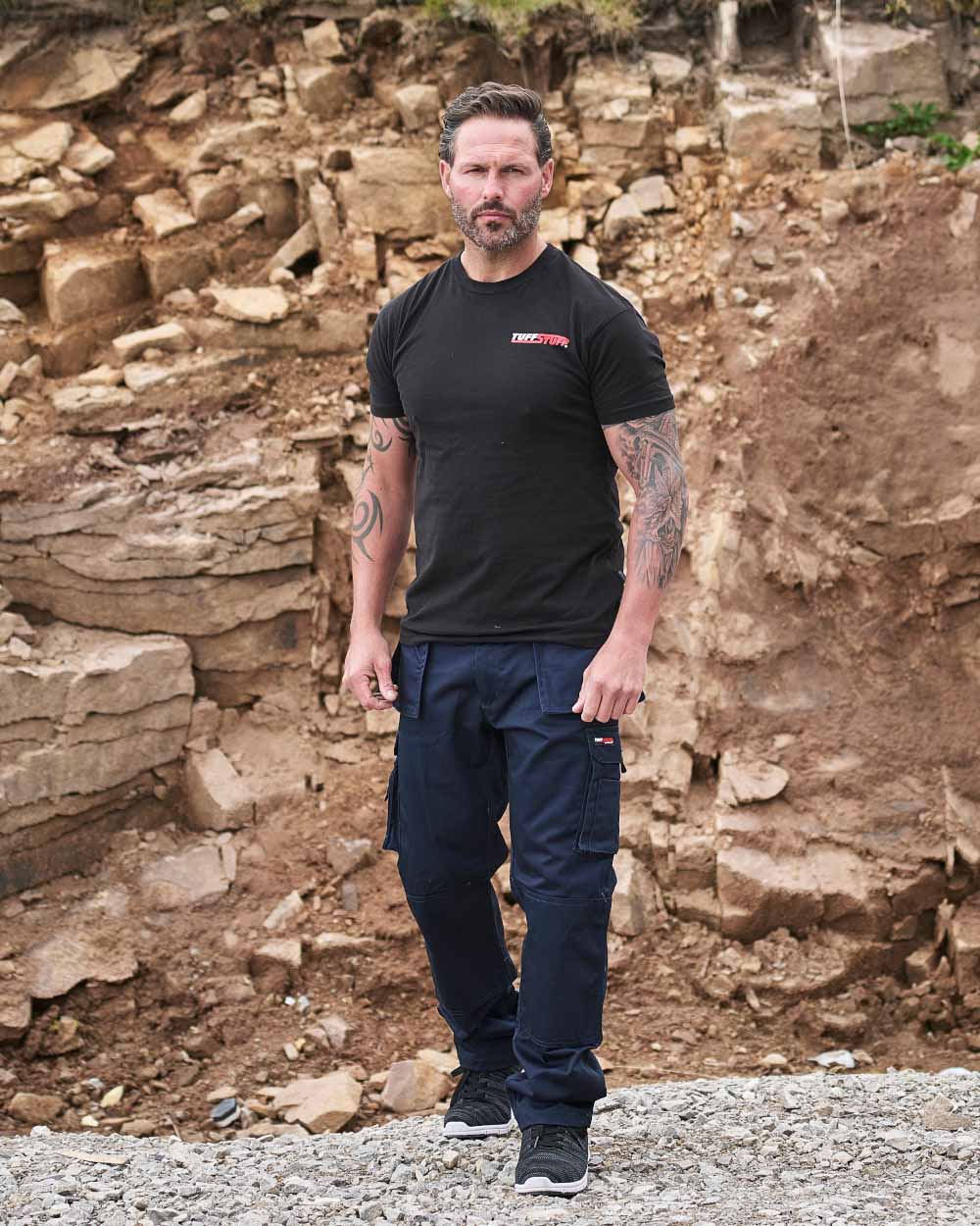 Navy Coloured TuffStuff Pro Work Trousers On A Warehouse Background 