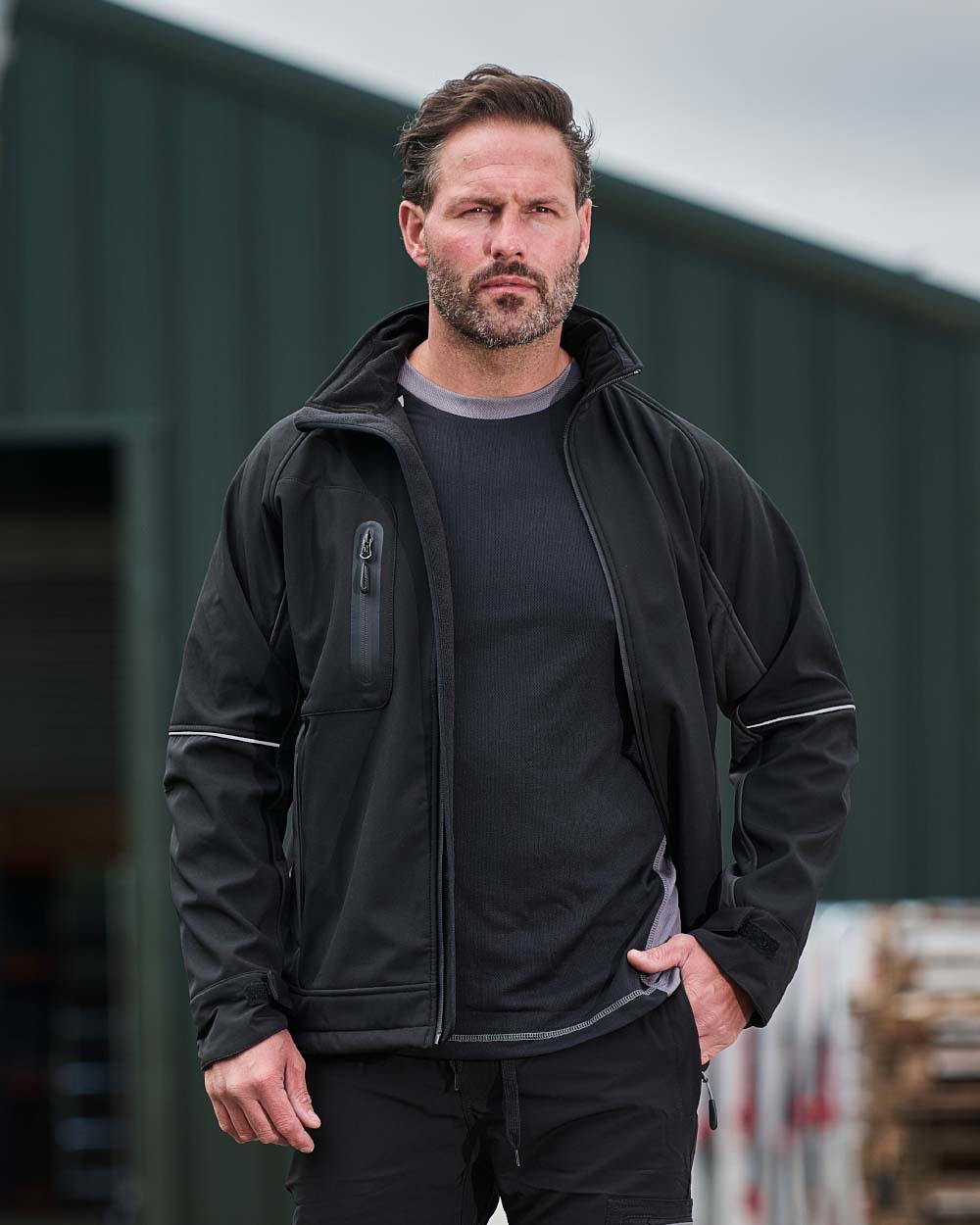 Black Coloured TuffStuff Stanton Waterproof Softshell Jacket On A Warehouse Background 