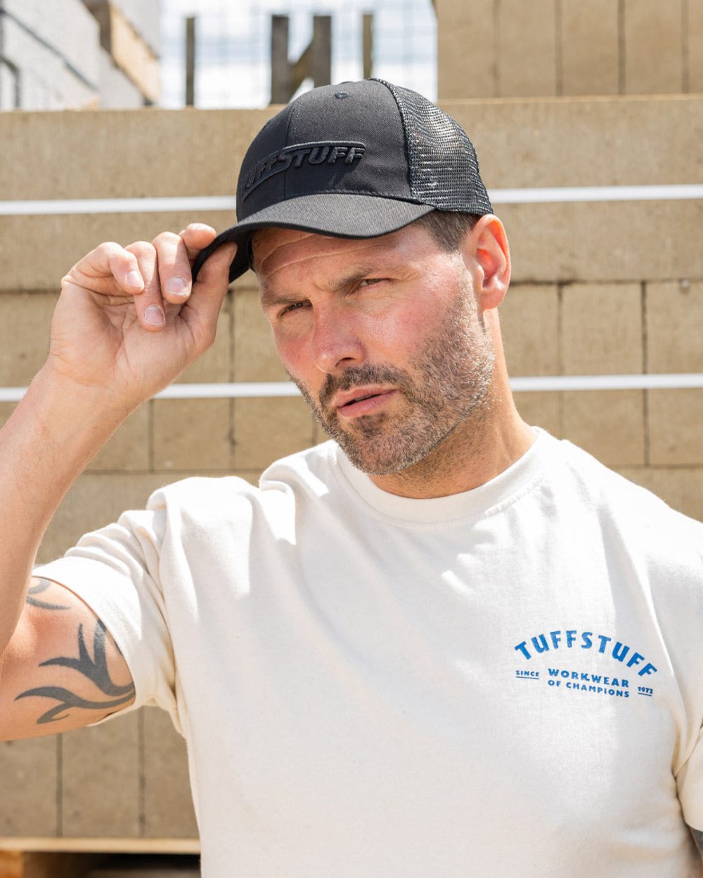 Black coloured TuffStuff Trucker Cap on construction background 