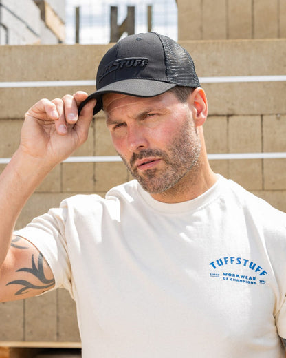 Black coloured TuffStuff Trucker Cap on construction background 