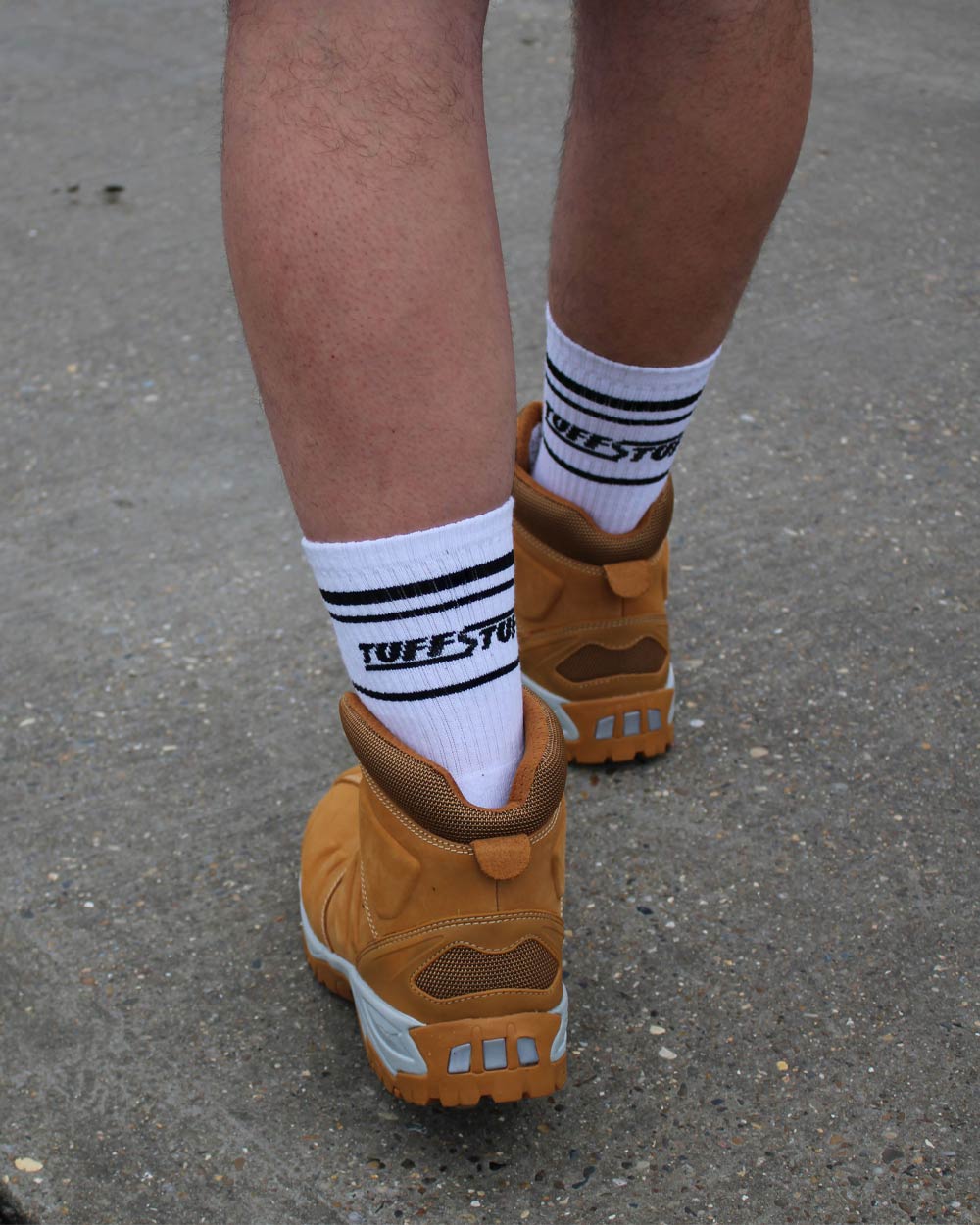 Brown workboots with white TuffStuff crew socks featuring on a concrete surface.