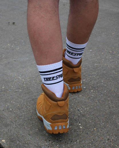 Brown workboots with white TuffStuff crew socks featuring on a concrete surface.