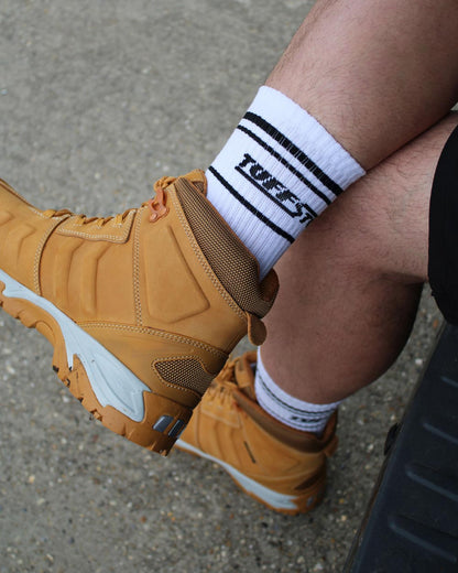 Brown work boot with white TuffStuff crew socks featuring on a concrete surface.